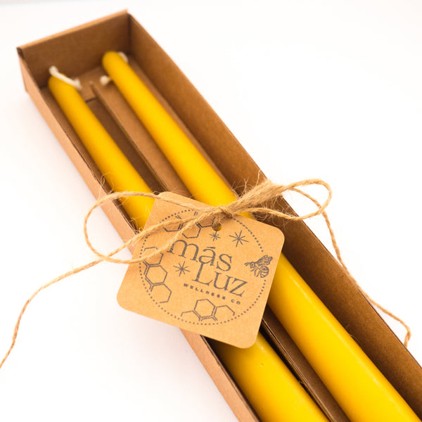 a set of two beeswax taper candles packaged in a box, wrapped with twine and the más luz wellness logo