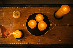 overhead shot of beeswax pillars lit on a wooden table