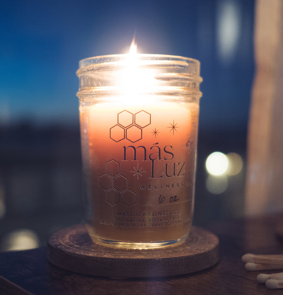 a lit up 8 oz beeswax jar candle on a coaster next to some matches