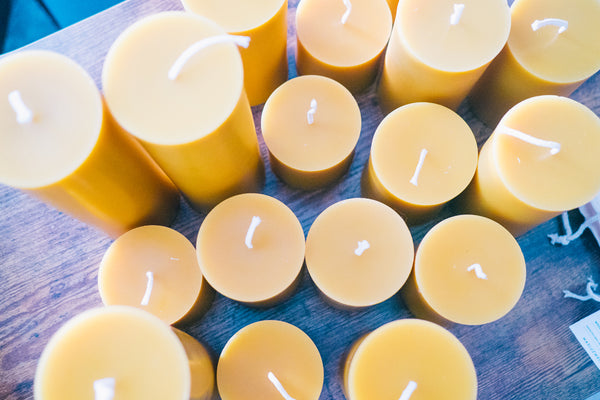 overhead shot of various sizes of beeswax pillar candles on a table