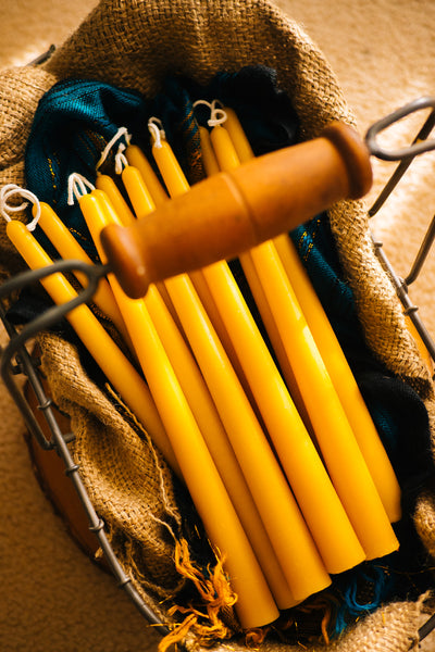 bundle of beeswax taper candles on a basket layered with a burlap bag